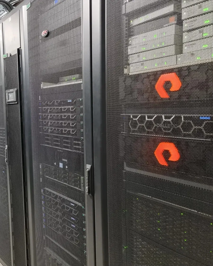 Baies de serveurs noires alignées dans un datacenter Adista, avec des baies de stockage Pure Storage au premier plan.